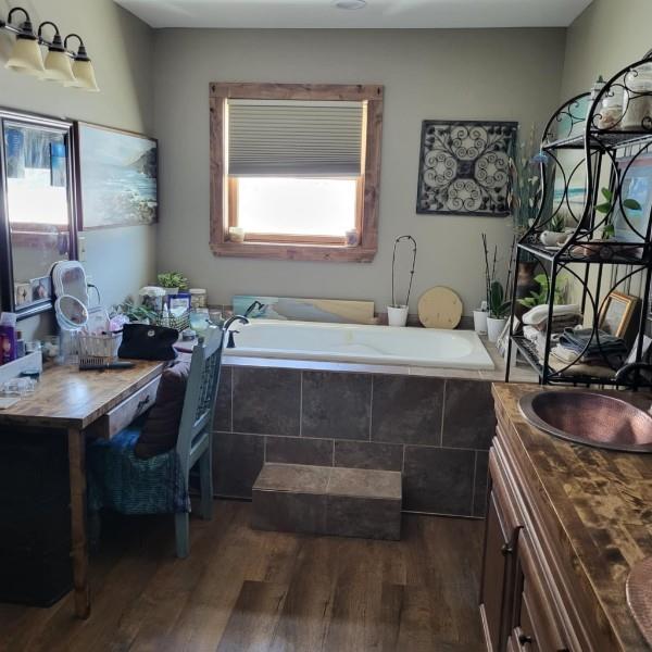 bathroom featuring vanity, hardwood / wood-style flooring, and tiled tub