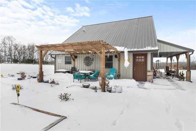 snow covered back of property featuring a pergola