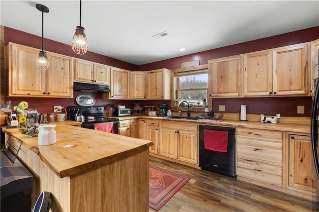 kitchen featuring black appliances, decorative light fixtures, butcher block counters, and light brown cabinetry