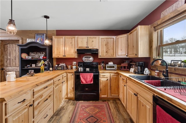 kitchen featuring butcher block counters, sink, black range with electric cooktop, decorative light fixtures, and light wood-type flooring