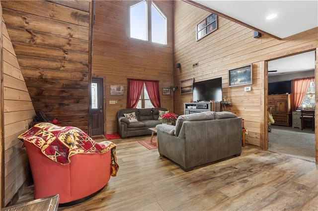 living room featuring hardwood / wood-style floors, wood walls, and a high ceiling