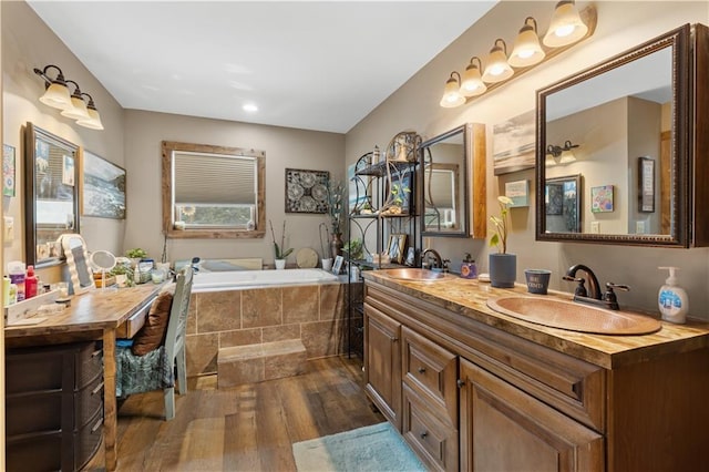 bathroom featuring hardwood / wood-style floors, vanity, and tiled bath