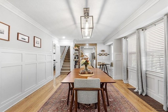 dining space featuring ornamental molding and light hardwood / wood-style flooring