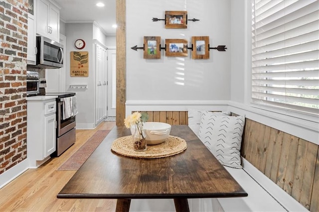 dining area with light hardwood / wood-style flooring and ornamental molding