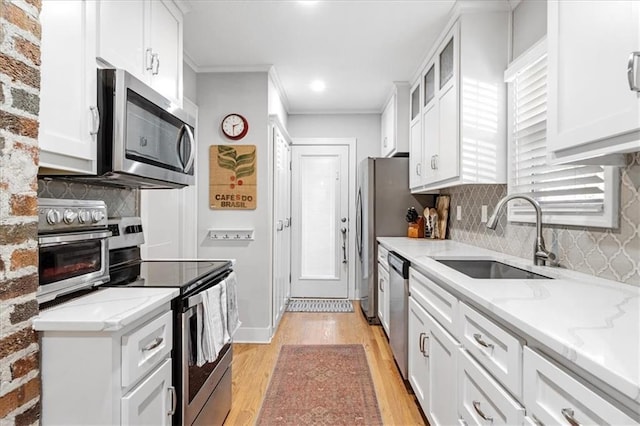 kitchen with light stone countertops, sink, light hardwood / wood-style floors, white cabinets, and appliances with stainless steel finishes