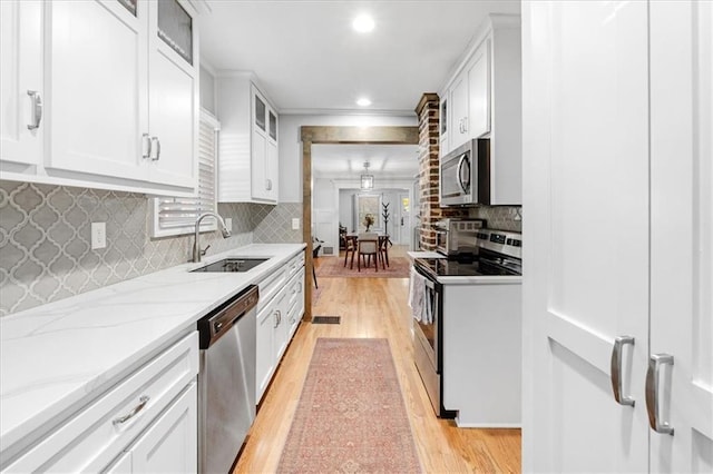 kitchen featuring white cabinets, stainless steel appliances, light stone countertops, and sink