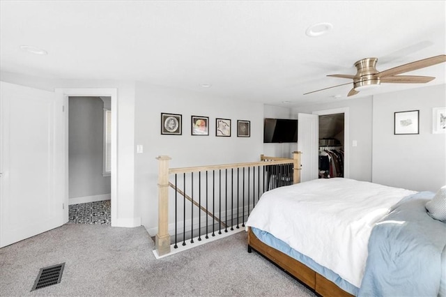 bedroom with a walk in closet, ceiling fan, a closet, and light carpet