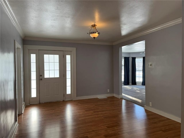 foyer entrance with crown molding, dark hardwood / wood-style flooring, and a textured ceiling