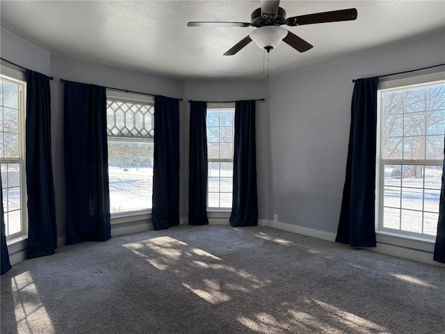 carpeted spare room with plenty of natural light and ceiling fan