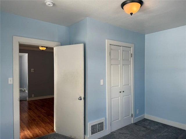 unfurnished bedroom featuring dark carpet and a closet