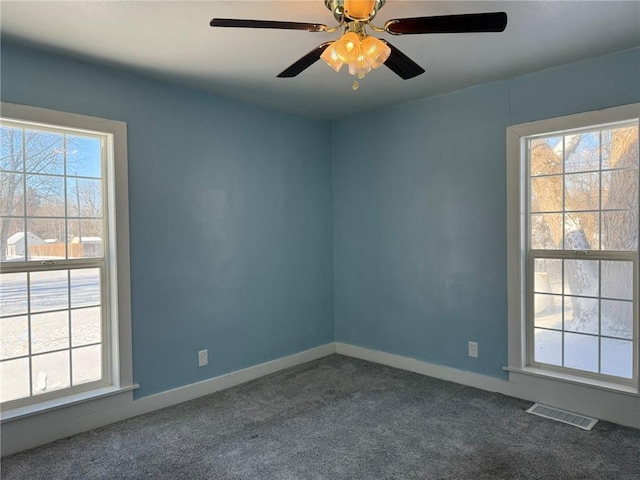 carpeted spare room featuring ceiling fan and a healthy amount of sunlight