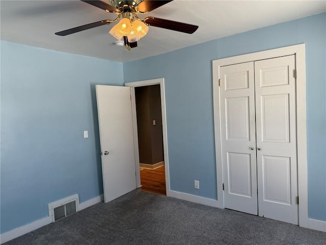 unfurnished bedroom featuring ceiling fan, a closet, and dark colored carpet