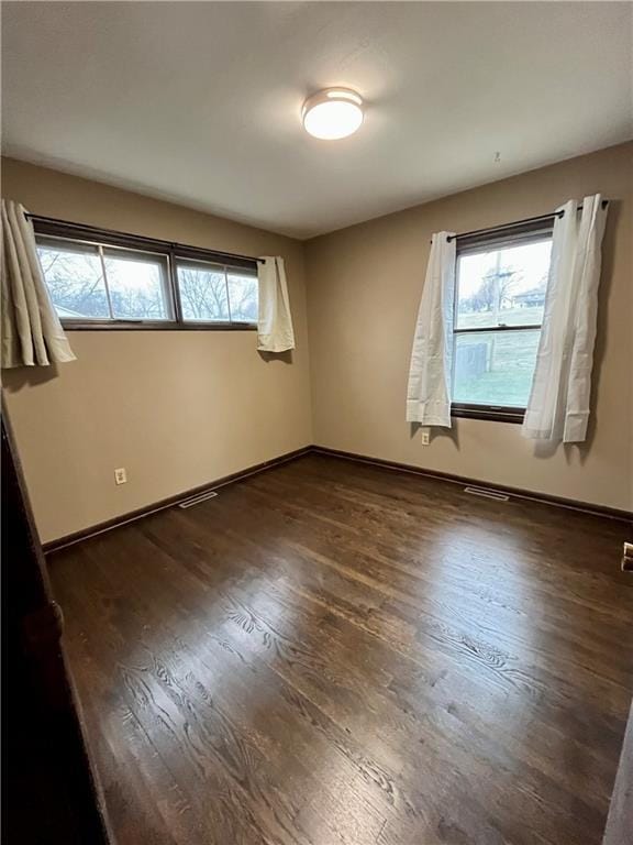 unfurnished room featuring dark hardwood / wood-style floors and plenty of natural light