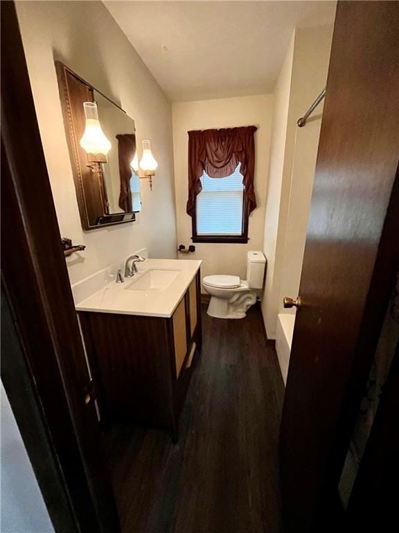 bathroom featuring vanity, hardwood / wood-style flooring, toilet, and a tub