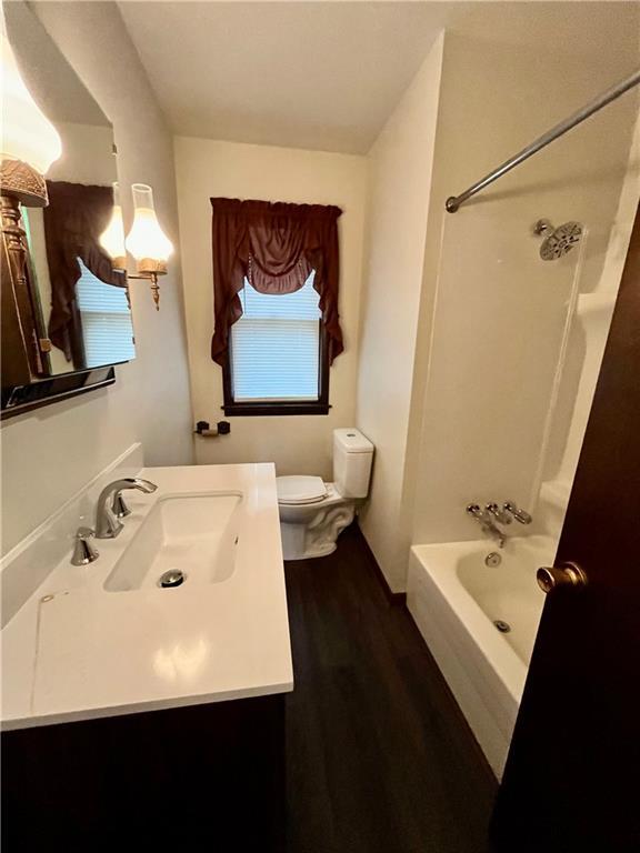 full bathroom featuring shower / bathing tub combination, vanity, hardwood / wood-style flooring, and toilet