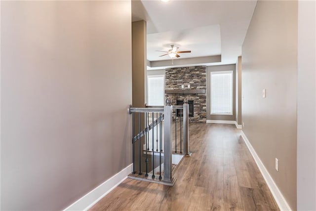 corridor with wood finished floors, an upstairs landing, and baseboards