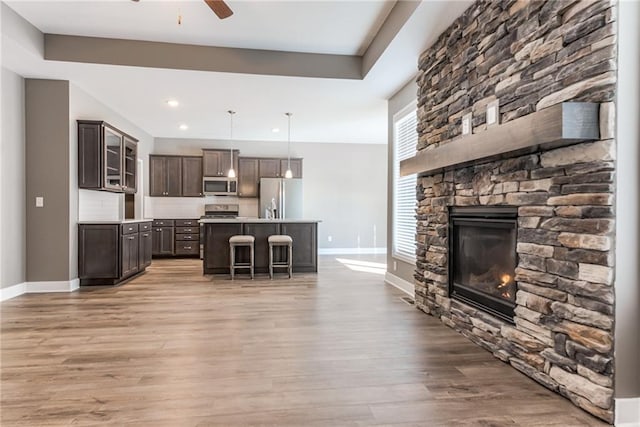 kitchen featuring light wood-style floors, appliances with stainless steel finishes, light countertops, baseboards, and dark brown cabinets