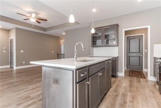 kitchen with light wood finished floors, backsplash, baseboards, and a sink