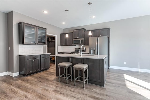 kitchen with baseboards, light wood-style flooring, a sink, light countertops, and appliances with stainless steel finishes