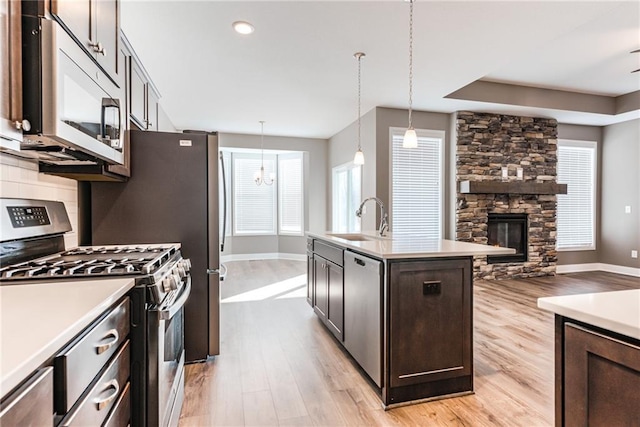 kitchen with a fireplace, a sink, dark brown cabinets, appliances with stainless steel finishes, and open floor plan