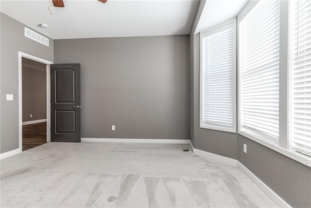 empty room featuring visible vents, baseboards, light colored carpet, and ceiling fan