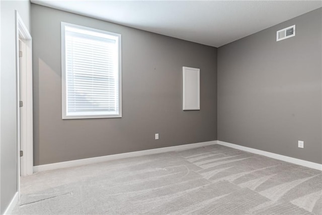 carpeted spare room featuring baseboards and visible vents