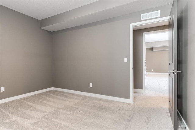 empty room with visible vents, baseboards, and light colored carpet