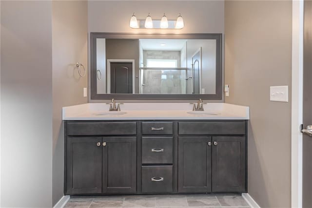 bathroom featuring double vanity, baseboards, a stall shower, and a sink