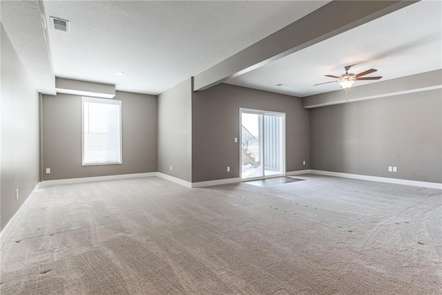 carpeted spare room featuring baseboards, visible vents, a wealth of natural light, and a textured ceiling