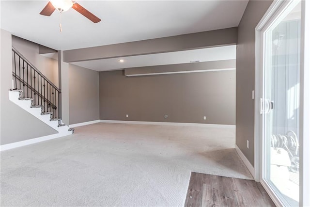 carpeted spare room featuring stairway, baseboards, and ceiling fan