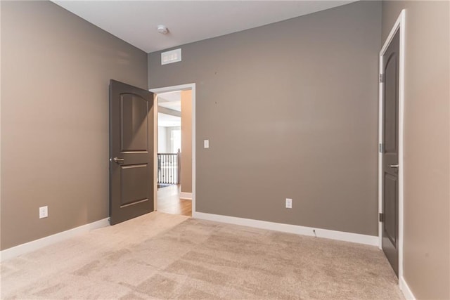 empty room featuring light carpet and baseboards