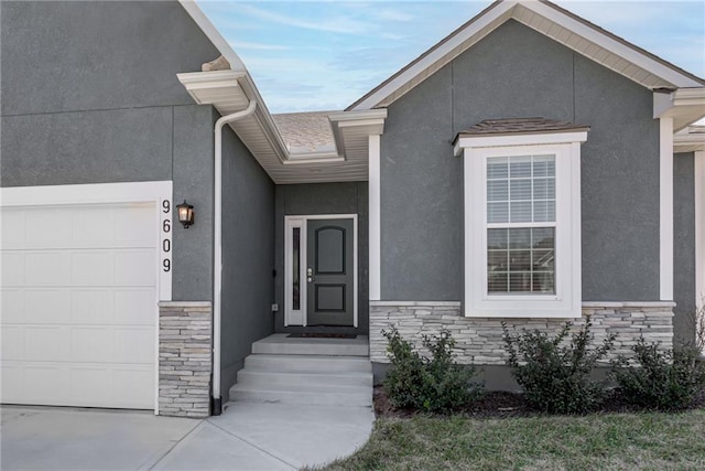 property entrance with a garage, stone siding, and stucco siding