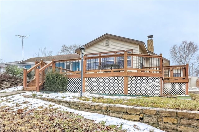 snow covered house with a wooden deck