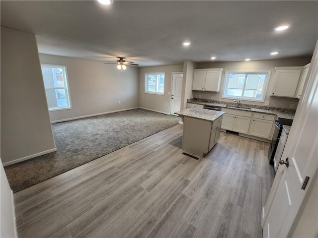 kitchen with a center island, light stone counters, white cabinetry, and sink