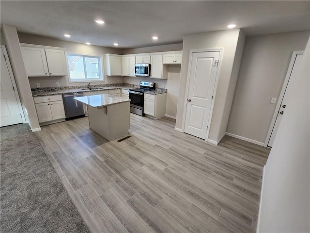 kitchen featuring sink, light hardwood / wood-style flooring, appliances with stainless steel finishes, a kitchen island, and white cabinetry