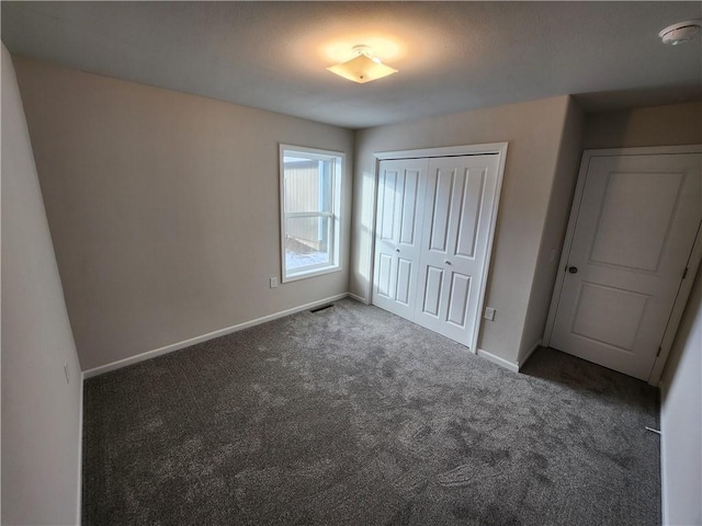 unfurnished bedroom with a closet and dark carpet