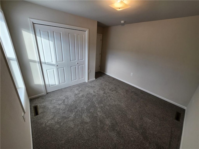 unfurnished bedroom featuring a closet and dark colored carpet