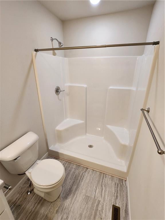 bathroom featuring toilet, wood-type flooring, and walk in shower