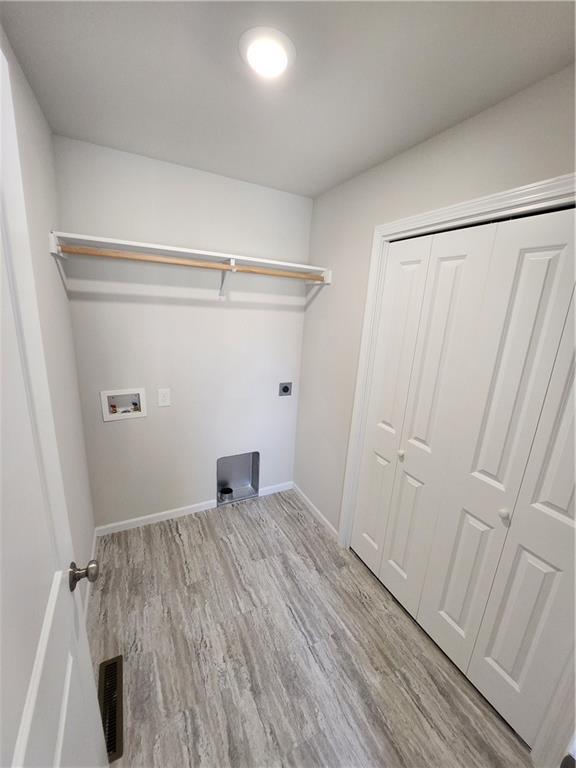 laundry area with washer hookup, electric dryer hookup, and light hardwood / wood-style floors