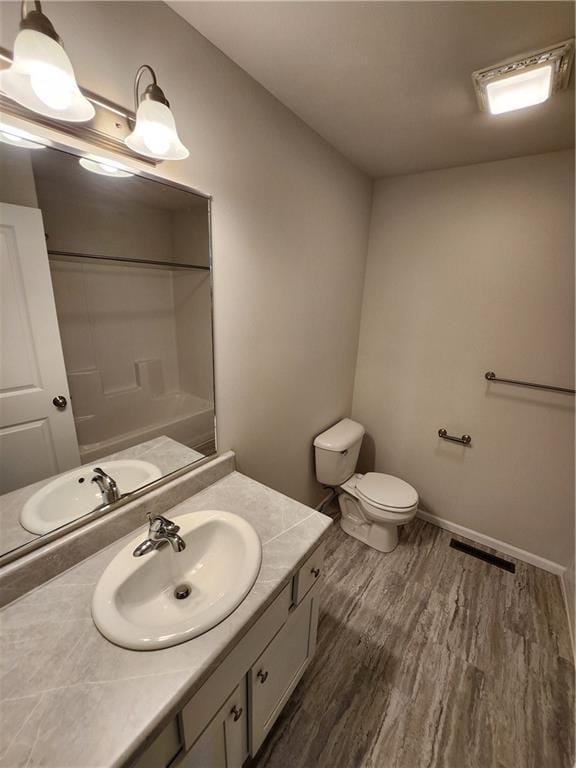 bathroom featuring wood-type flooring, vanity, toilet, and walk in shower