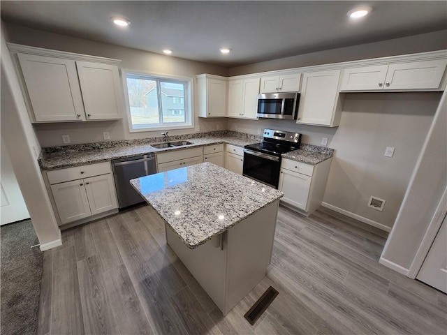 kitchen featuring white cabinetry, sink, a kitchen island, and appliances with stainless steel finishes