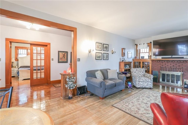 living room with hardwood / wood-style floors, a brick fireplace, and a wealth of natural light