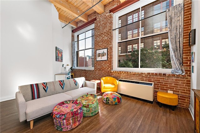 living area featuring beam ceiling, radiator, wood ceiling, brick wall, and wood finished floors