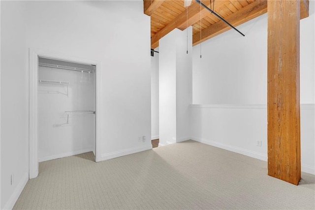 unfurnished bedroom with wood ceiling, carpet floors, a closet, and beam ceiling