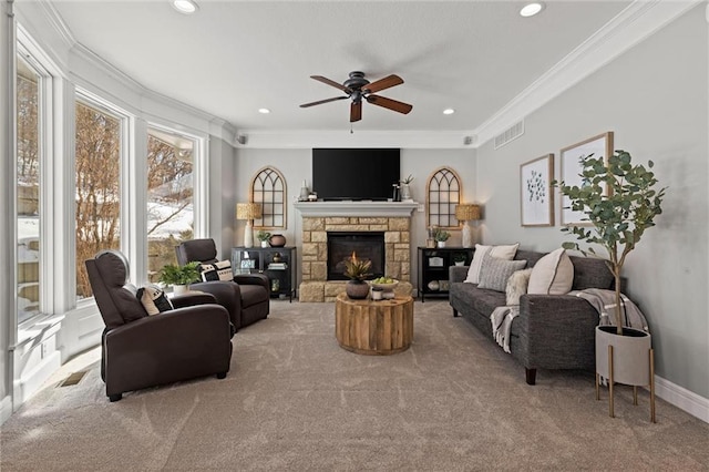 living room with crown molding, a healthy amount of sunlight, a stone fireplace, and light colored carpet