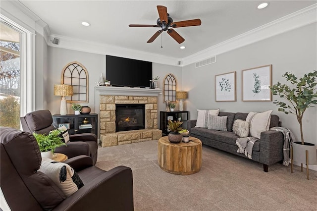 carpeted living room with ceiling fan, crown molding, and a fireplace