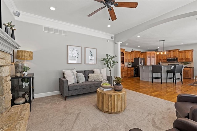 living room with ornate columns, ornamental molding, light hardwood / wood-style floors, and ceiling fan