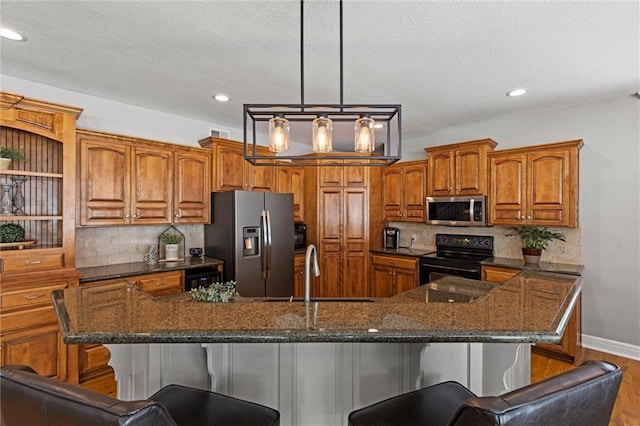 kitchen featuring a breakfast bar, a large island with sink, appliances with stainless steel finishes, and sink