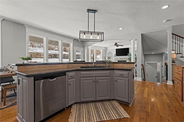 kitchen with an island with sink, ceiling fan, gray cabinetry, stainless steel dishwasher, and sink