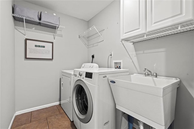 laundry room featuring cabinets, washer and clothes dryer, dark tile patterned floors, and sink